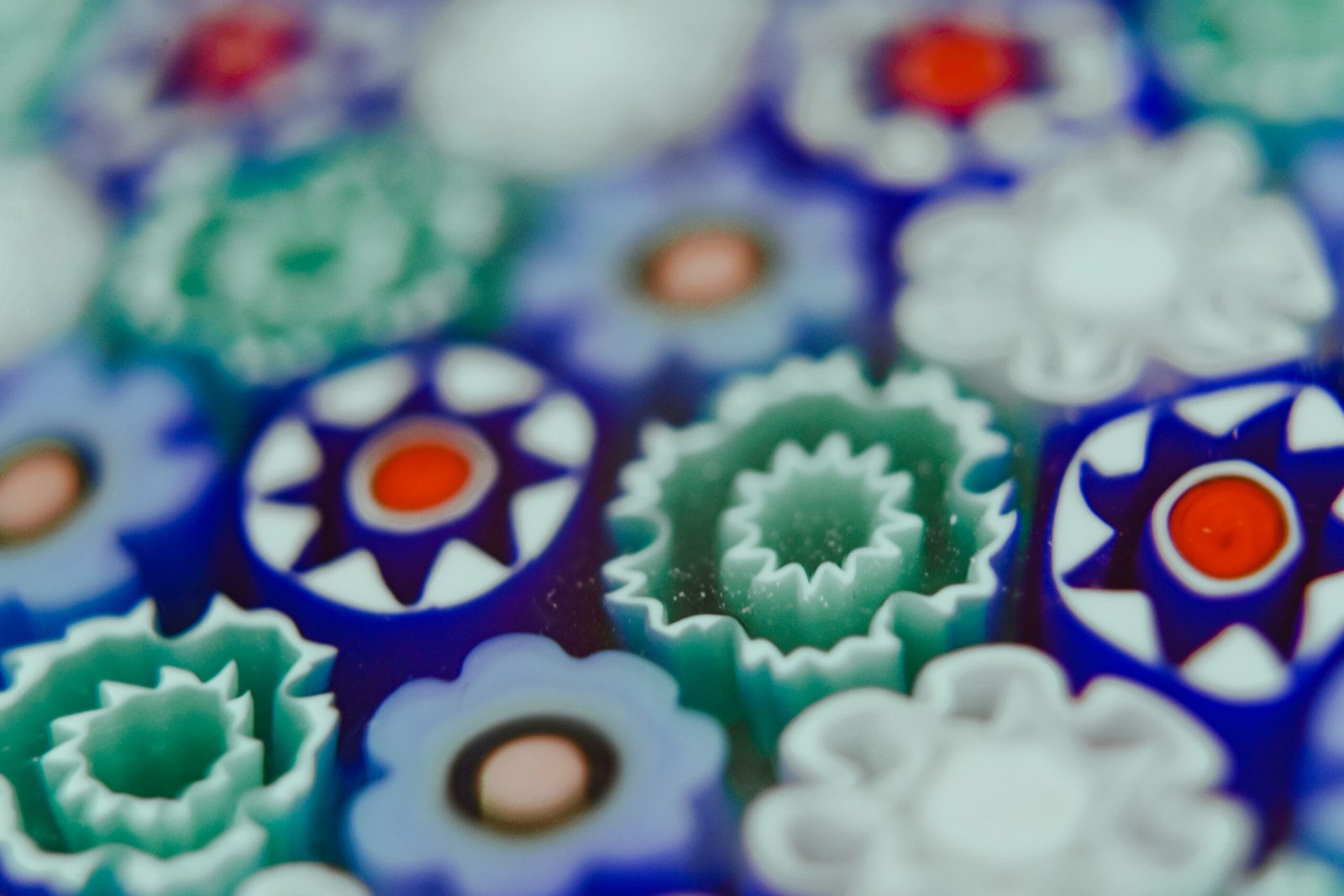 A close-up of multicoloured millefiori glass canes, showing the patterned cross-sections used to build paperweight designs.