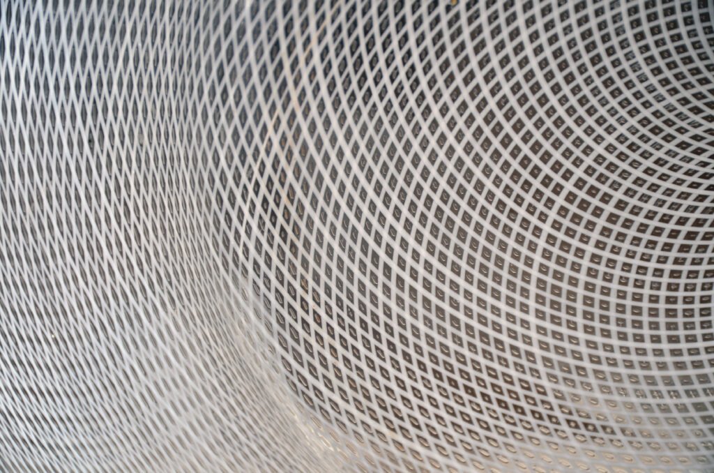 Close-up of the wall of a Venetian glass vessel showing a fine diagonal lattice of white glass threads crossing to form a regular diamond mesh.